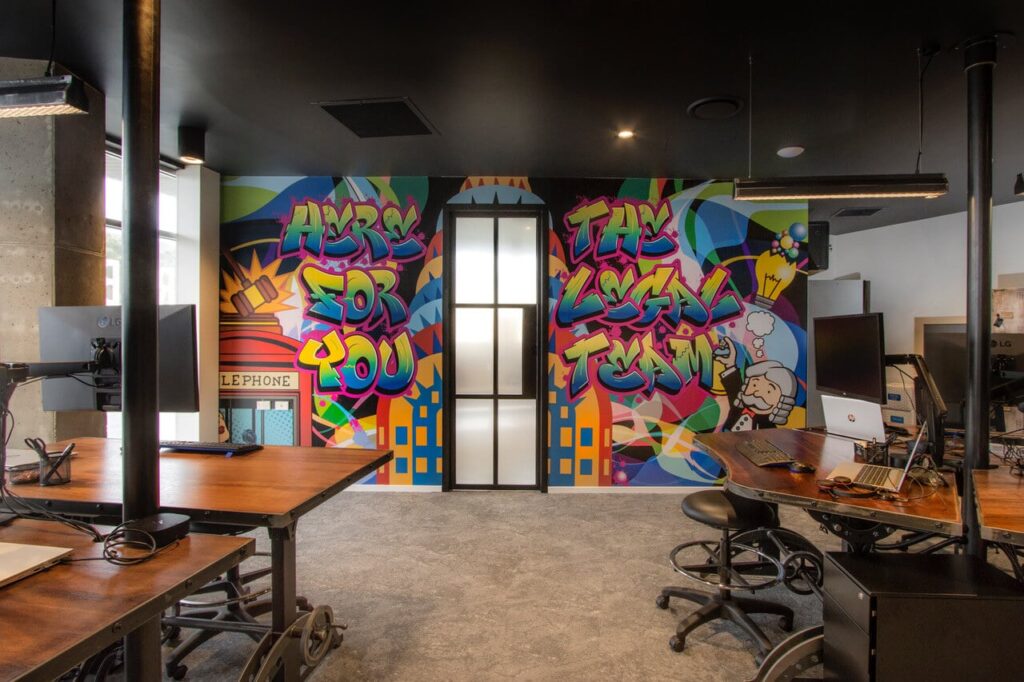 Colorful graffiti mural in modern office space with desks and chairs.