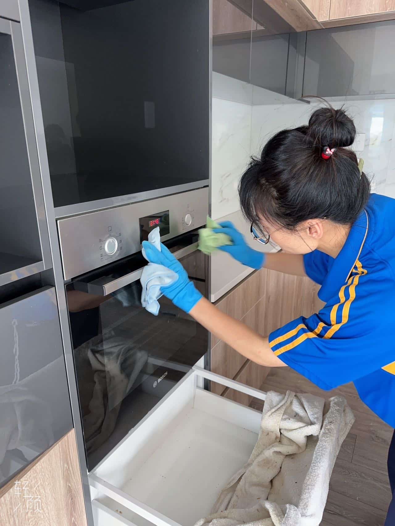 Person cleaning an oven with a cloth and gloves.