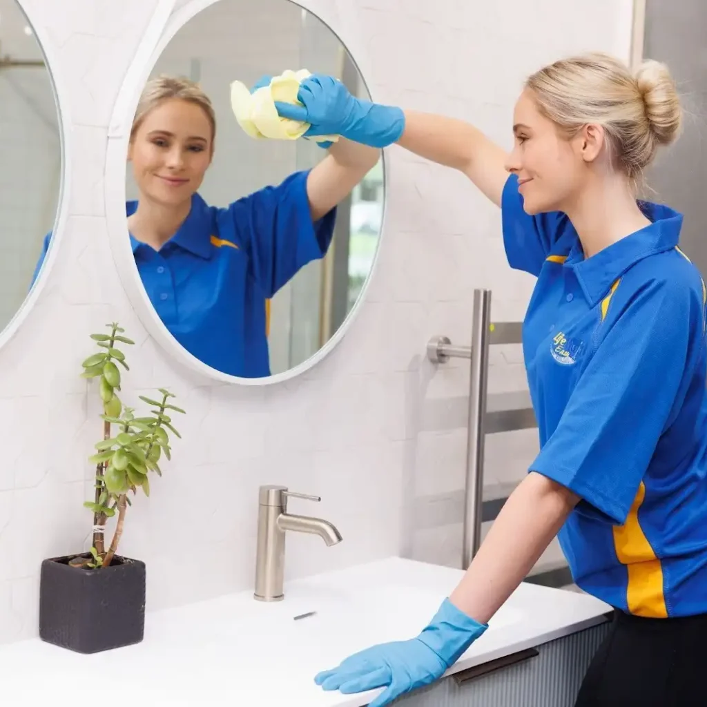 Professional cleaner wiping bathroom mirror