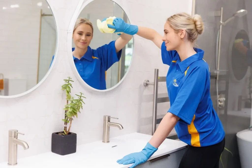 Professional cleaner wiping bathroom mirror