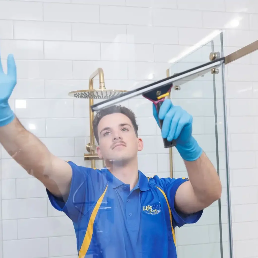 Professional cleaners wiping shower glass