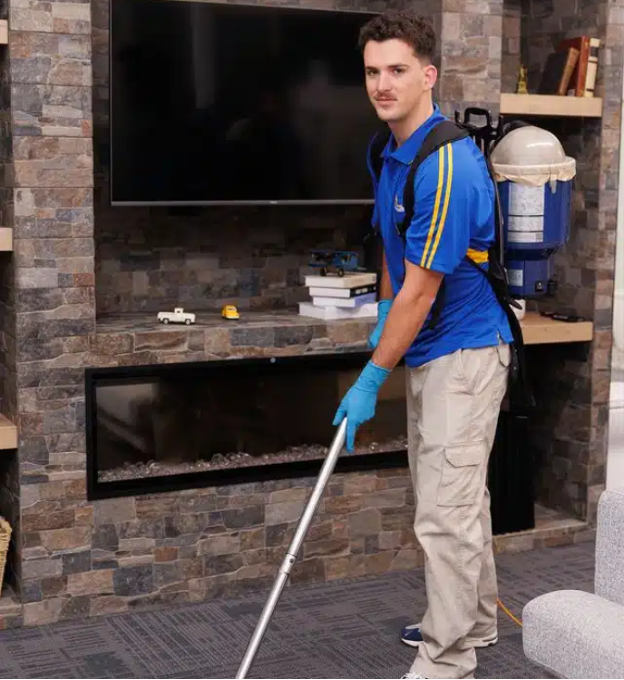 Cleaning staff vacuuming a living room while wearing a backpack vacuum and gloves